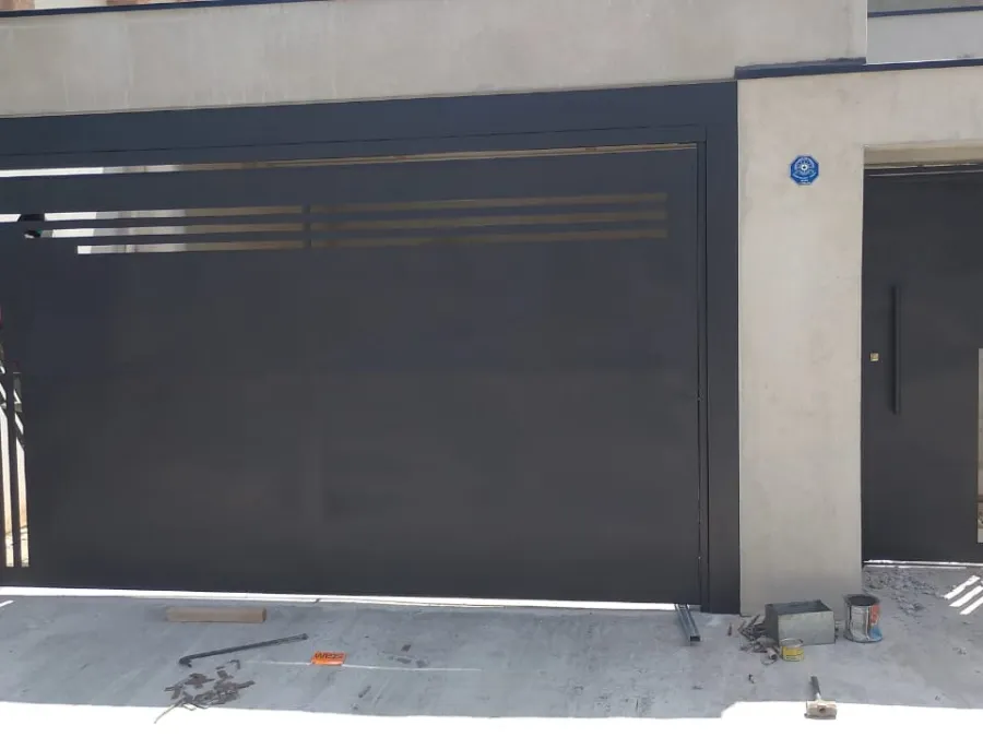 Portão basculante metálico preto com porta social ao lado